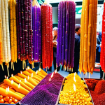 A market stall overflowing with colorful Churchkhela hanging like edible candles, tourists mesmerized by the display, showcasing a variety of colors from deep purple to golden brown.